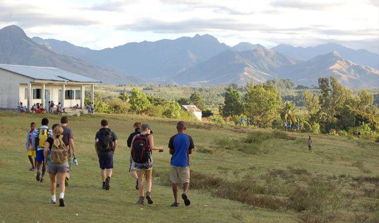 Group of people walking across grass with mountains on the horizon