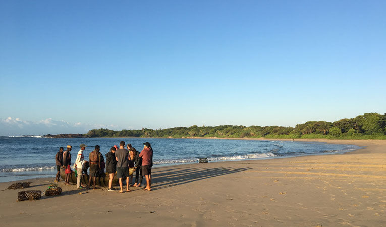  A team standing on the beach next to a boat
