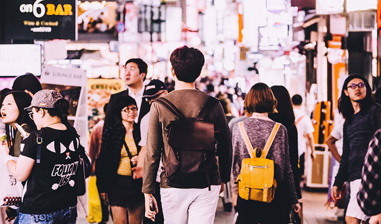 Man wearing backpack walking through busy crowd in the street