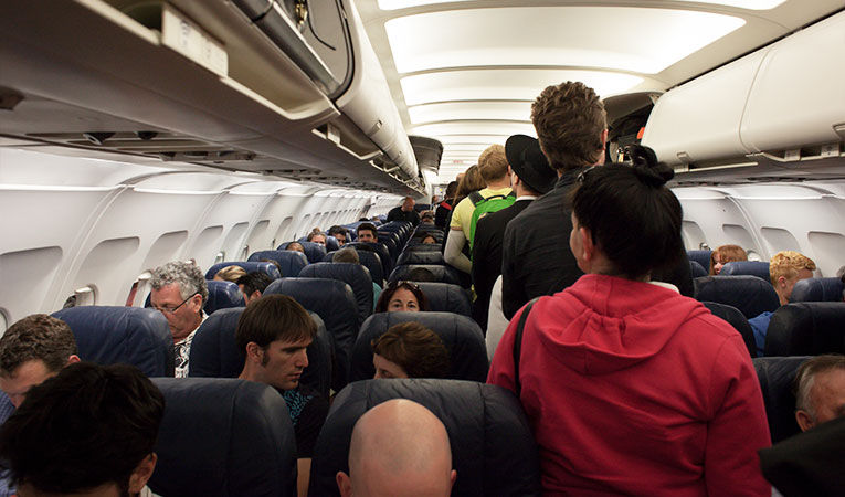 Пассажиры самолета проходят по проходу самолета во время посадки
